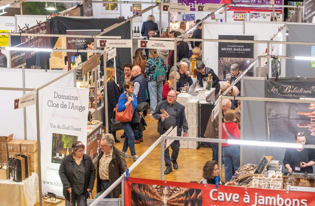 Foule de visiteurs explorant un salon gastronomique avec divers stands de produits locaux et options de dégustation.